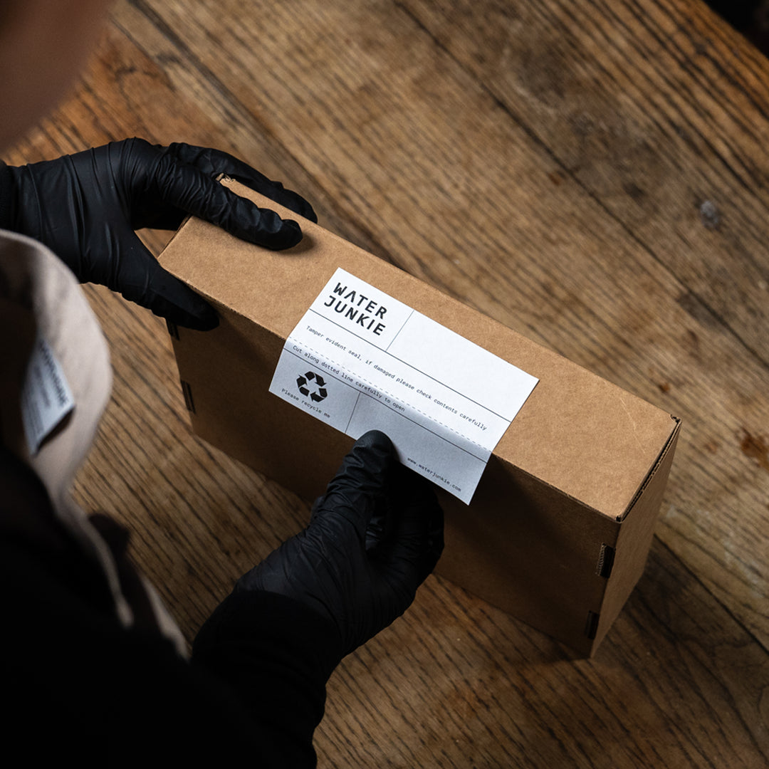 A person sticking a Water Junkie label onto a taster pack delivery box